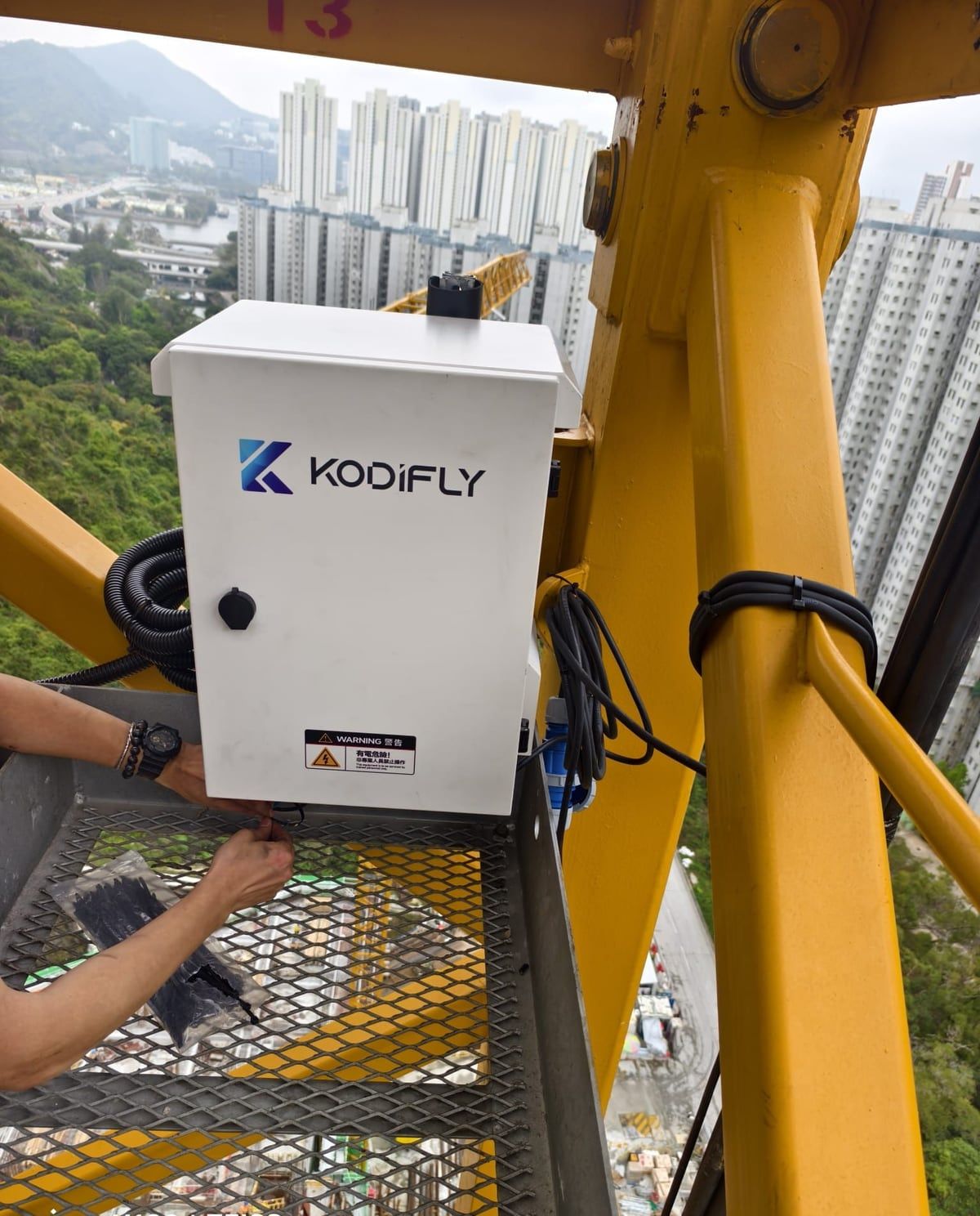 A Kodifly equipment cabinet being installed on a tower crane at a Hong Kong housing site