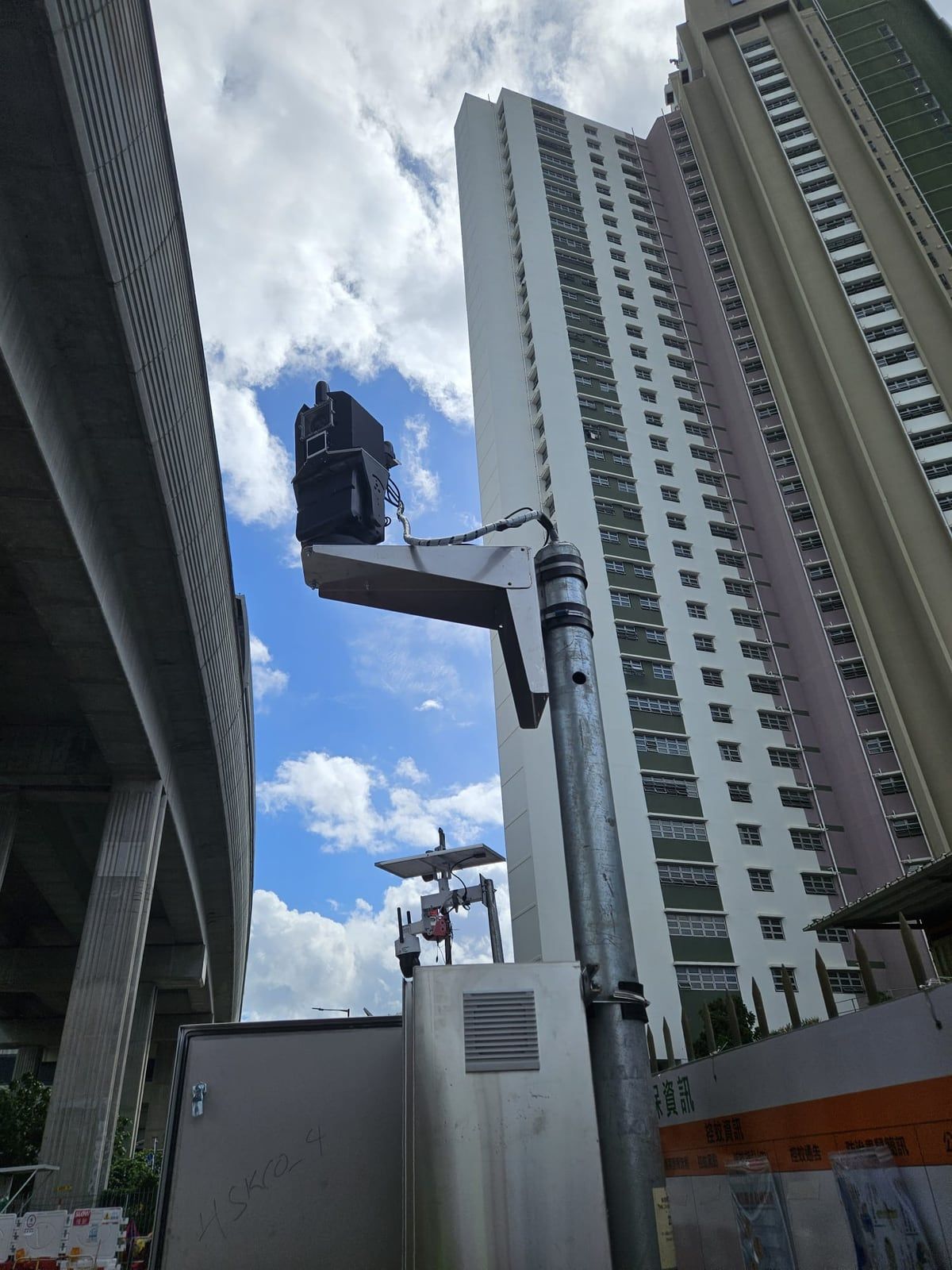 A Kodifly LiDAR unit on a pole beside a flyover and a public housing estate