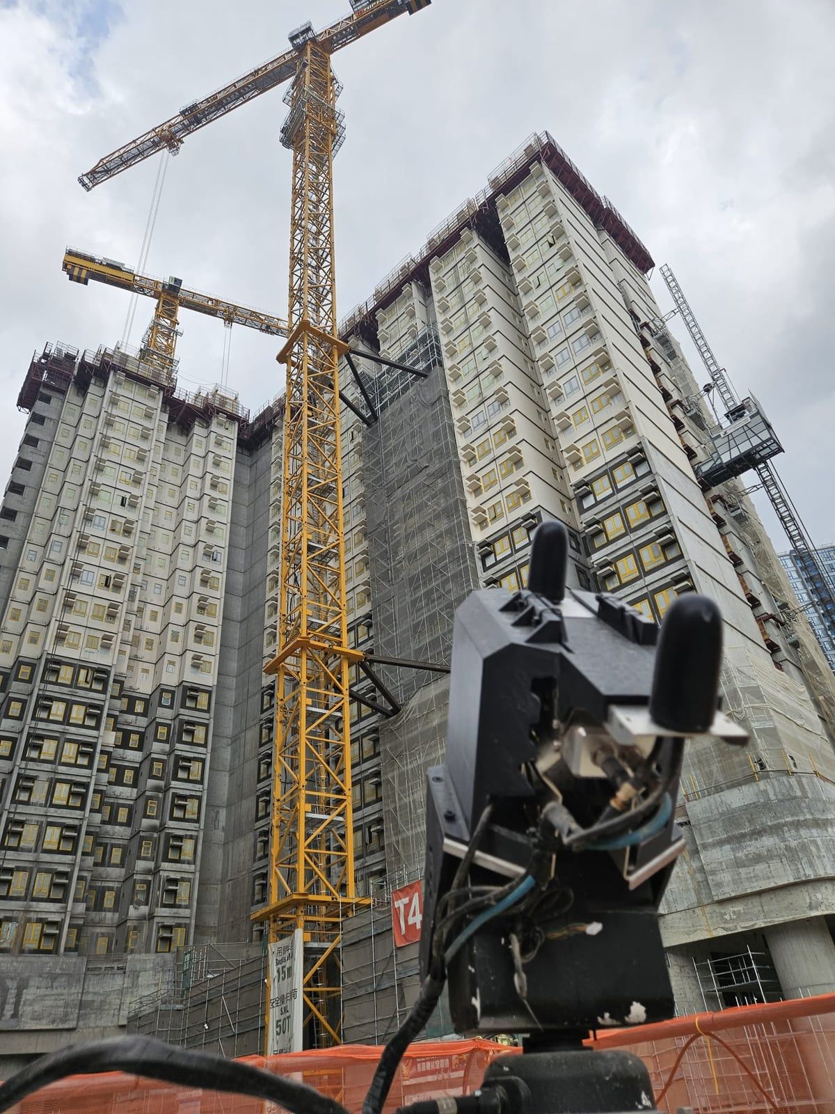 A Kodifly fixed-point LiDAR unit in front of public housing blocks and tower cranes under construction